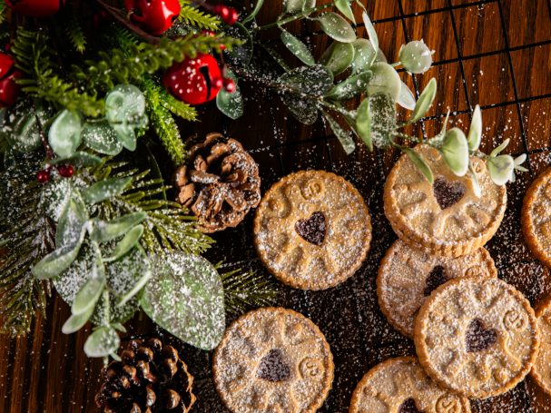 Festive cookies with heart shapes, surrounded by pinecones and greenery.